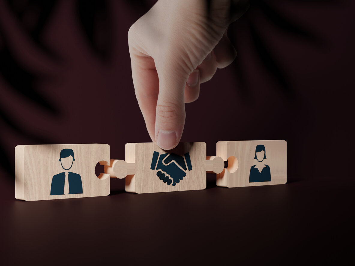 A hand connecting puzzle pieces representing a male and female figure with a handshake symbol, illustrating how family law mediation can help achieve a more amicable divorce.