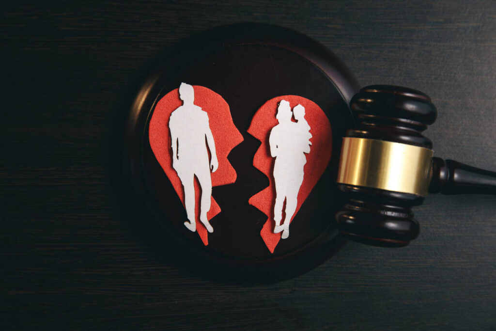 A wooden gavel next to broken red heart shapes with paper cutouts of a man and a woman, symbolizing high-conflict divorce in California.